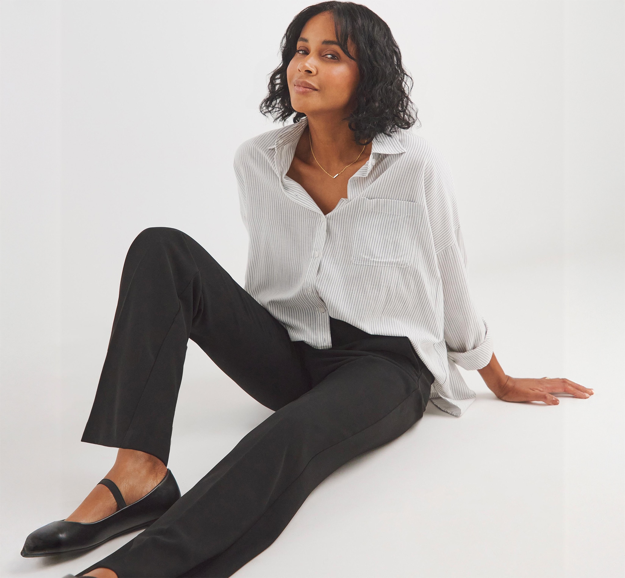 Lady sat down on floor with white blouse and black trousers