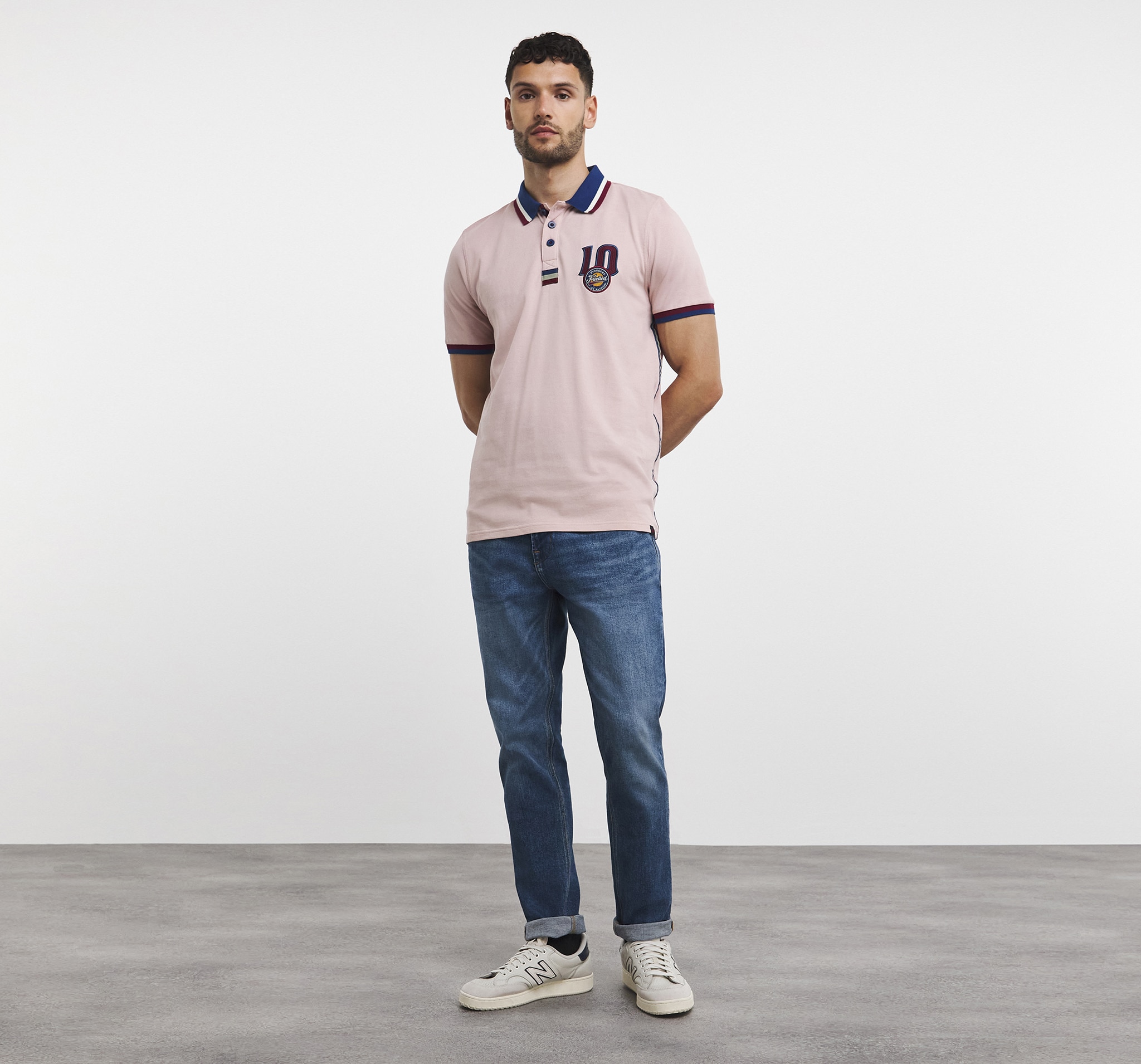 Man wearing a dusky pink polo shirt and jeans